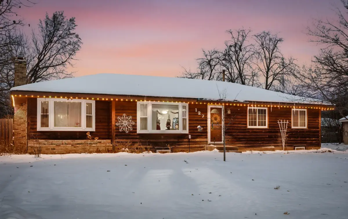 Warm white permanent roofline lighting on a home at dusk in the snow