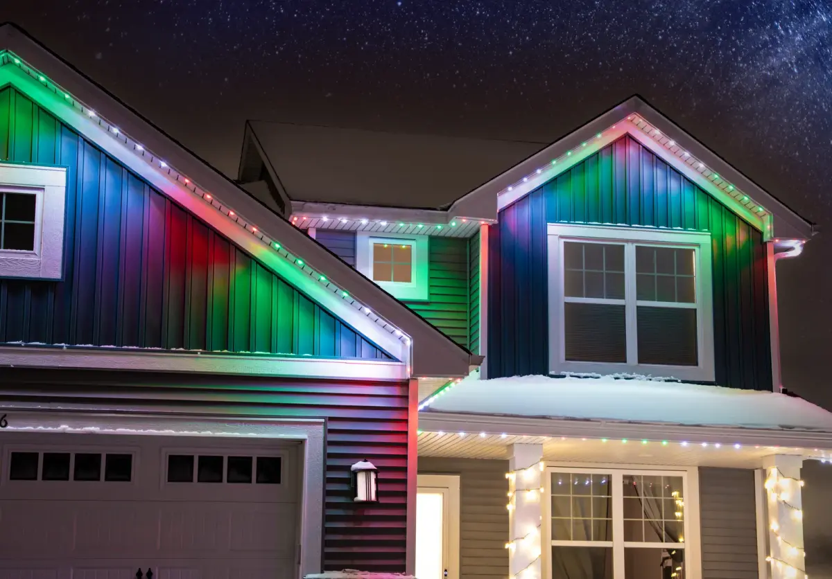 Two story Capital Region home with multi color permanent roofline lighting at night