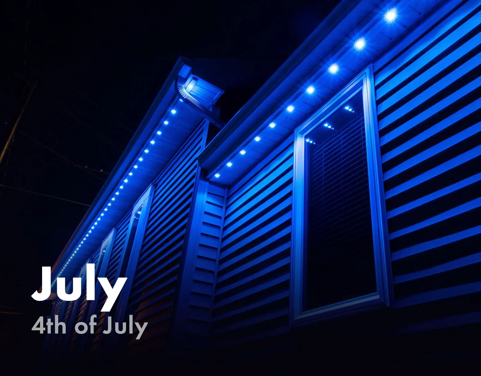 Home siding and roofline lit in blue for the 4th of July