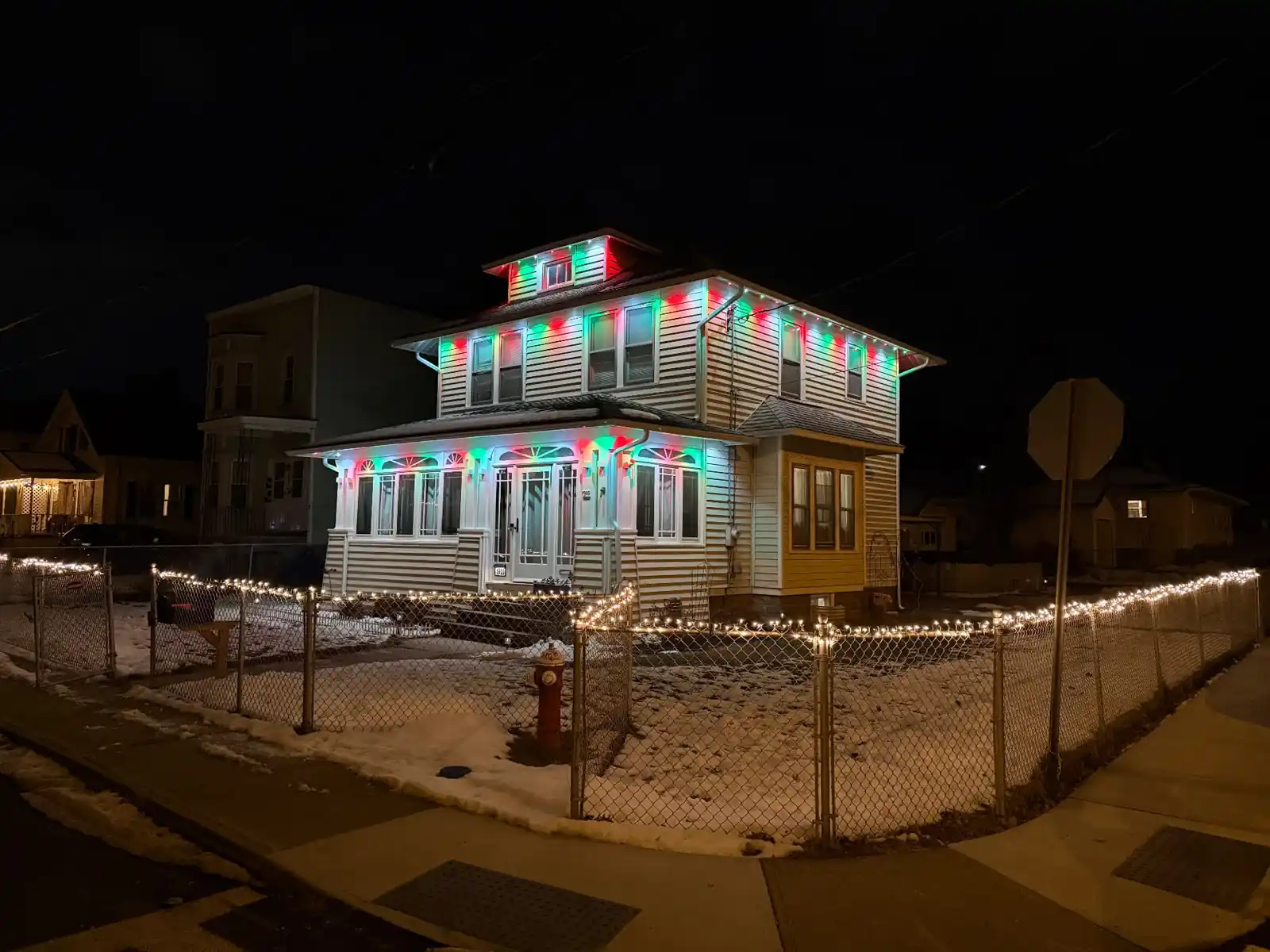 Three story home with multi color eaves and fence lights