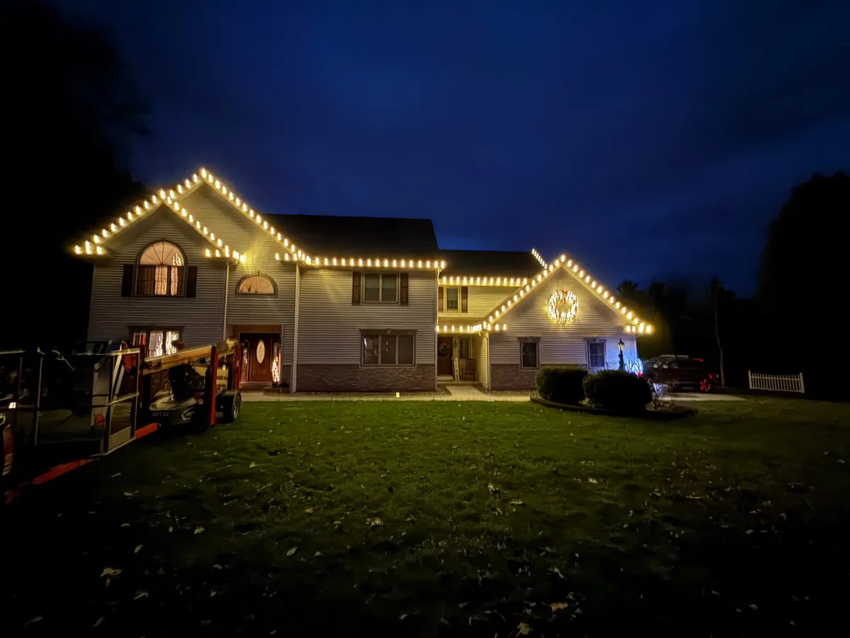 Warm white C9 Christmas rooflines and a lit gable wreath at dusk